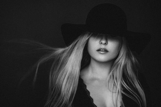 Beautiful blonde woman wearing a hat, artistic film portrait in black and white for fashion campaign and beauty brands