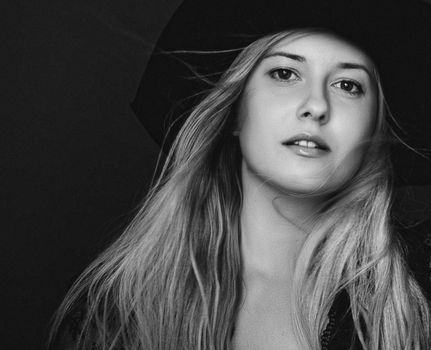 Beautiful blonde woman wearing a hat, artistic film portrait in black and white for fashion campaign and beauty brands