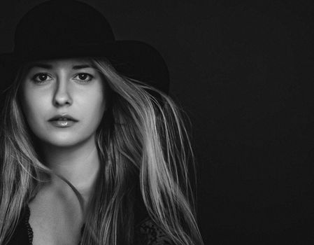 Beautiful blonde woman wearing a hat, artistic film portrait in black and white for fashion campaign and beauty brands