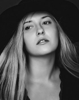 Beautiful blonde woman wearing a hat, artistic film portrait in black and white for fashion campaign and beauty brands