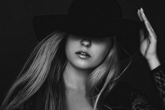 Beautiful blonde woman wearing a hat, artistic film portrait in black and white for fashion campaign and beauty brands