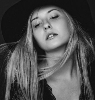 Beautiful blonde woman wearing a hat, artistic film portrait in black and white for fashion campaign and beauty brands