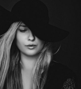 Beautiful blonde woman wearing a hat, artistic film portrait in black and white for fashion campaign and beauty brands