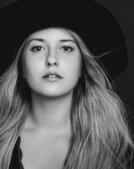 Beautiful blonde woman wearing a hat, artistic film portrait in black and white for fashion campaign and beauty brands