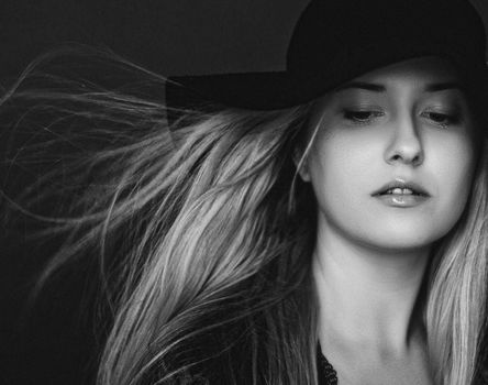 Beautiful blonde woman wearing a hat, artistic film portrait in black and white for fashion campaign and beauty brands