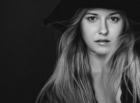 Beautiful blonde woman wearing a hat, artistic film portrait in black and white for fashion campaign and beauty brands