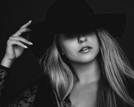 Beautiful blonde woman wearing a hat, artistic film portrait in black and white for fashion campaign and beauty brands