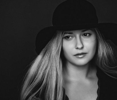 Beautiful blonde woman wearing a hat, artistic film portrait in black and white for fashion campaign and beauty brands