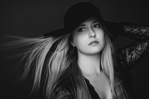 Beautiful blonde woman wearing a hat, artistic film portrait in black and white for fashion campaign and beauty brands