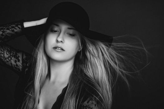 Beautiful blonde woman wearing a hat, artistic film portrait in black and white for fashion campaign and beauty brands