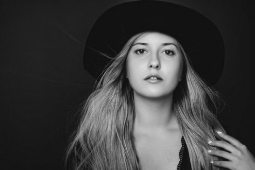 Beautiful blonde woman wearing a hat, artistic film portrait in black and white for fashion campaign and beauty brands