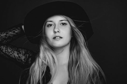 Beautiful blonde woman wearing a hat, artistic film portrait in black and white for fashion campaign and beauty brands