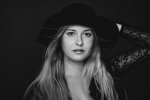 Beautiful blonde woman wearing a hat, artistic film portrait in black and white for fashion campaign and beauty brands