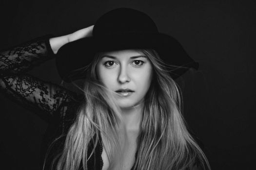 Beautiful blonde woman wearing a hat, artistic film portrait in black and white for fashion campaign and beauty brands