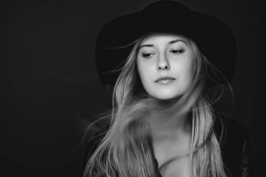 Beautiful blonde woman wearing a hat, artistic film portrait in black and white for fashion campaign and beauty brands