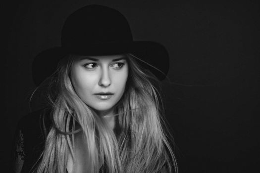 Beautiful blonde woman wearing a hat, artistic film portrait in black and white for fashion campaign and beauty brands