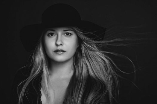 Beautiful blonde woman wearing a hat, artistic film portrait in black and white for fashion campaign and beauty brands