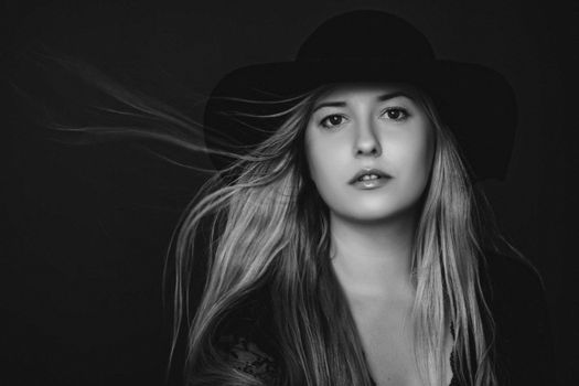 Beautiful blonde woman wearing a hat, artistic film portrait in black and white for fashion campaign and beauty brands