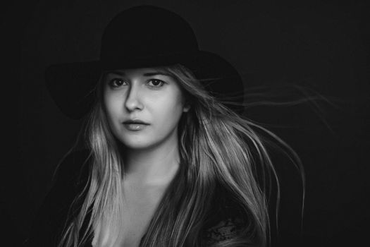 Beautiful blonde woman wearing a hat, artistic film portrait in black and white for fashion campaign and beauty brands