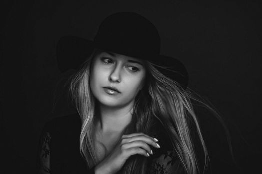 Beautiful blonde woman wearing a hat, artistic film portrait in black and white for fashion campaign and beauty brands