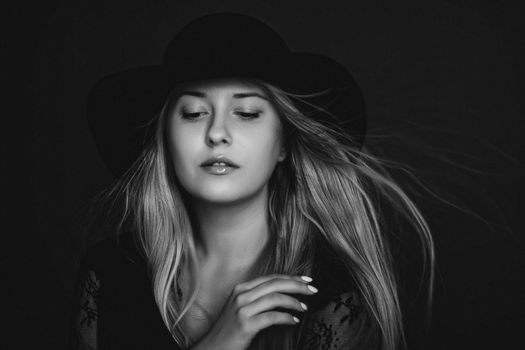 Beautiful blonde woman wearing a hat, artistic film portrait in black and white for fashion campaign and beauty brands