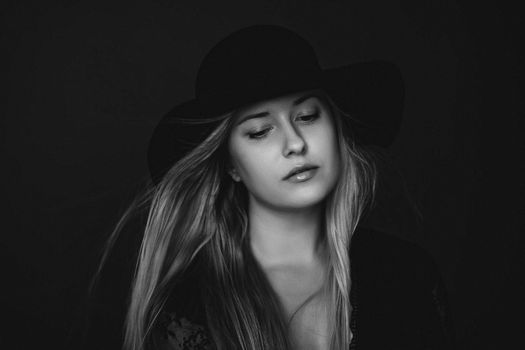 Beautiful blonde woman wearing a hat, artistic film portrait in black and white for fashion campaign and beauty brands