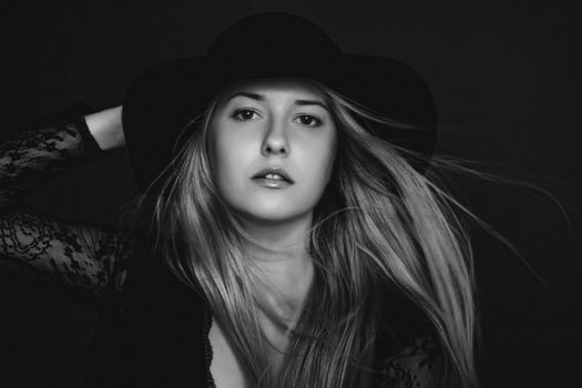 Beautiful blonde woman wearing a hat, artistic film portrait in black and white for fashion campaign and beauty brands