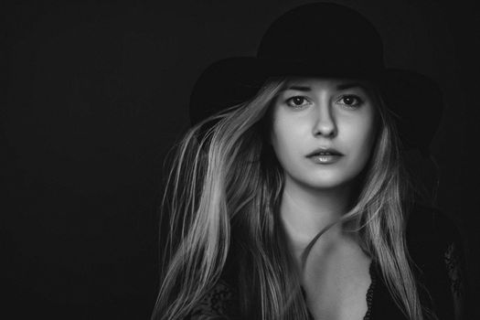 Beautiful blonde woman wearing a hat, artistic film portrait in black and white for fashion campaign and beauty brands