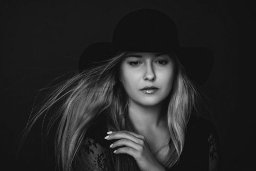 Beautiful blonde woman wearing a hat, artistic film portrait in black and white for fashion campaign and beauty brands