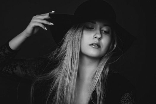 Beautiful blonde woman wearing a hat, artistic film portrait in black and white for fashion campaign and beauty brands