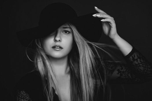 Beautiful blonde woman wearing a hat, artistic film portrait in black and white for fashion campaign and beauty brands