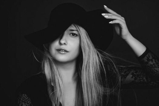 Beautiful blonde woman wearing a hat, artistic film portrait in black and white for fashion campaign and beauty brands