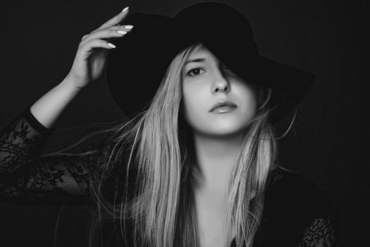 Beautiful blonde woman wearing a hat, artistic film portrait in black and white for fashion campaign and beauty brands