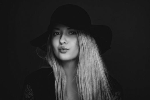 Beautiful blonde woman wearing a hat, artistic film portrait in black and white for fashion campaign and beauty brands