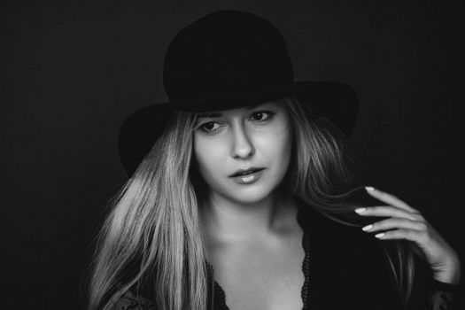 Beautiful blonde woman wearing a hat, artistic film portrait in black and white for fashion campaign and beauty brands