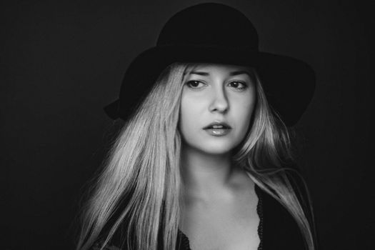 Beautiful blonde woman wearing a hat, artistic film portrait in black and white for fashion campaign and beauty brands