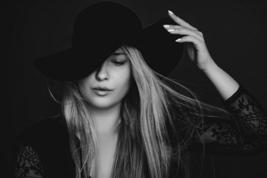 Beautiful blonde woman wearing a hat, artistic film portrait in black and white for fashion campaign and beauty brands