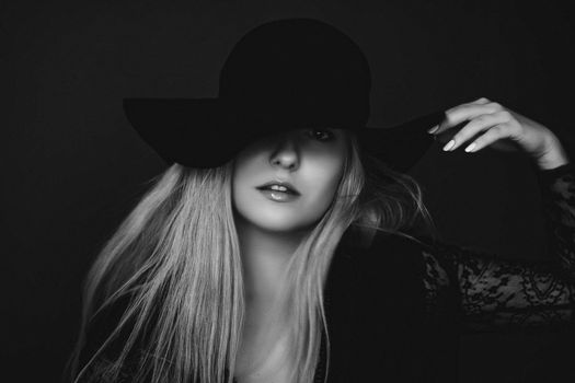 Beautiful blonde woman wearing a hat, artistic film portrait in black and white for fashion campaign and beauty brands