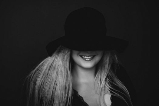 Beautiful blonde woman wearing a hat, artistic film portrait in black and white for fashion campaign and beauty brands