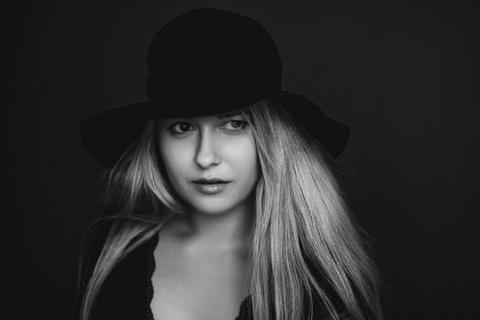 Beautiful blonde woman wearing a hat, artistic film portrait in black and white for fashion campaign and beauty brands