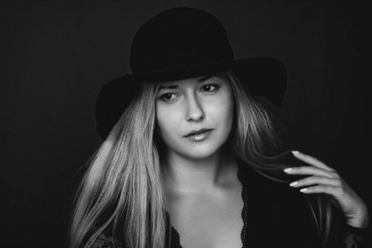 Beautiful blonde woman wearing a hat, artistic film portrait in black and white for fashion campaign and beauty brands