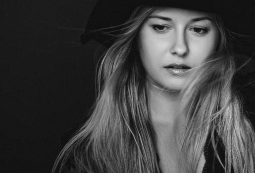 Beautiful blonde woman wearing a hat, artistic film portrait in black and white for fashion campaign and beauty brands