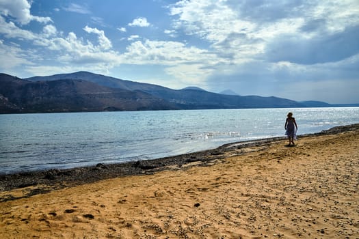 Girl in a dress on a sandy beach on the island of Kefalonia in Greece