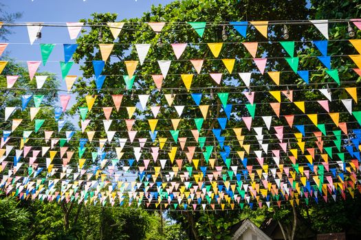 Multi colored triangular Flags Hanging in the sky on outdoor road at celebration party