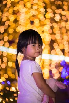 little asian girl hug doll and bokeh background on Christmas day