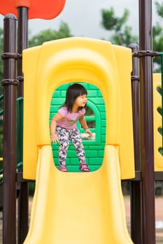 little girl having fun to play slider in the playground in summer time