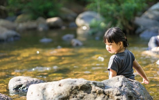 little asian girl playing in waterfall stream