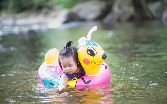 Little girl with pink rubber ring in nature water on holiday