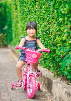 happy little girl ride a bicycle in the park