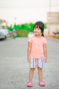 portrait of happy little girl standing on the road